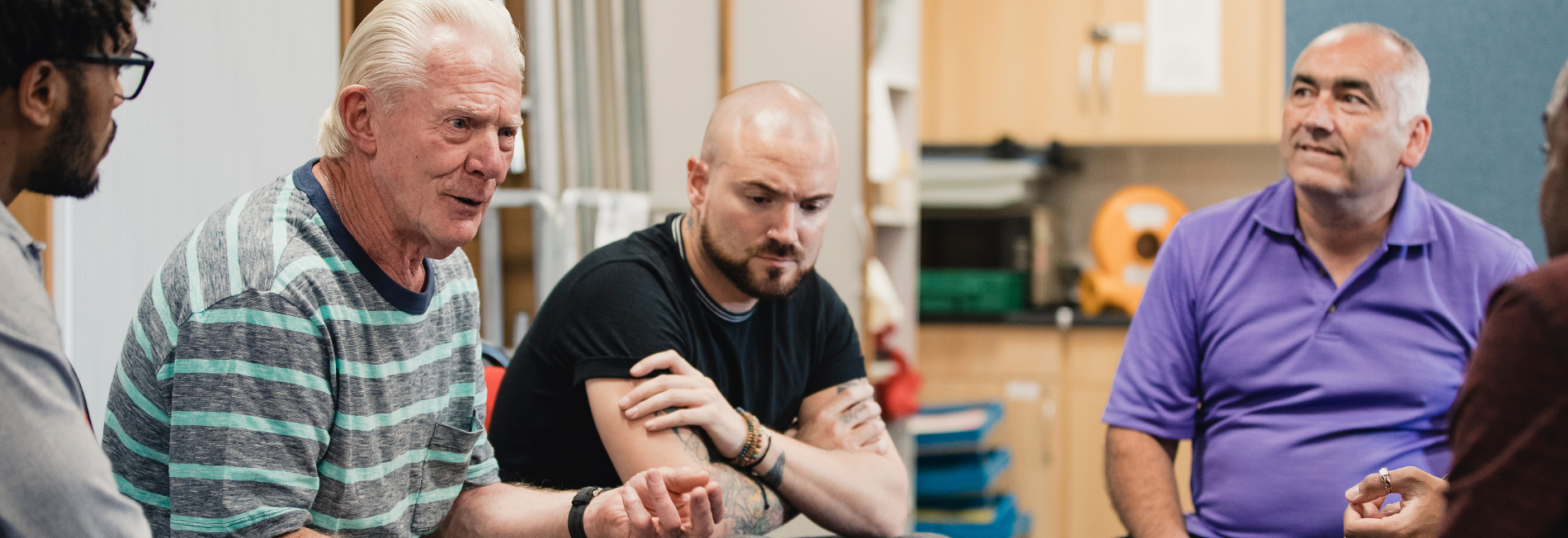 Group of men in a Men's Support Group session. Older man is speaking while the group listens.