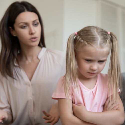 Mother talking to child who is upset with her arms crossed