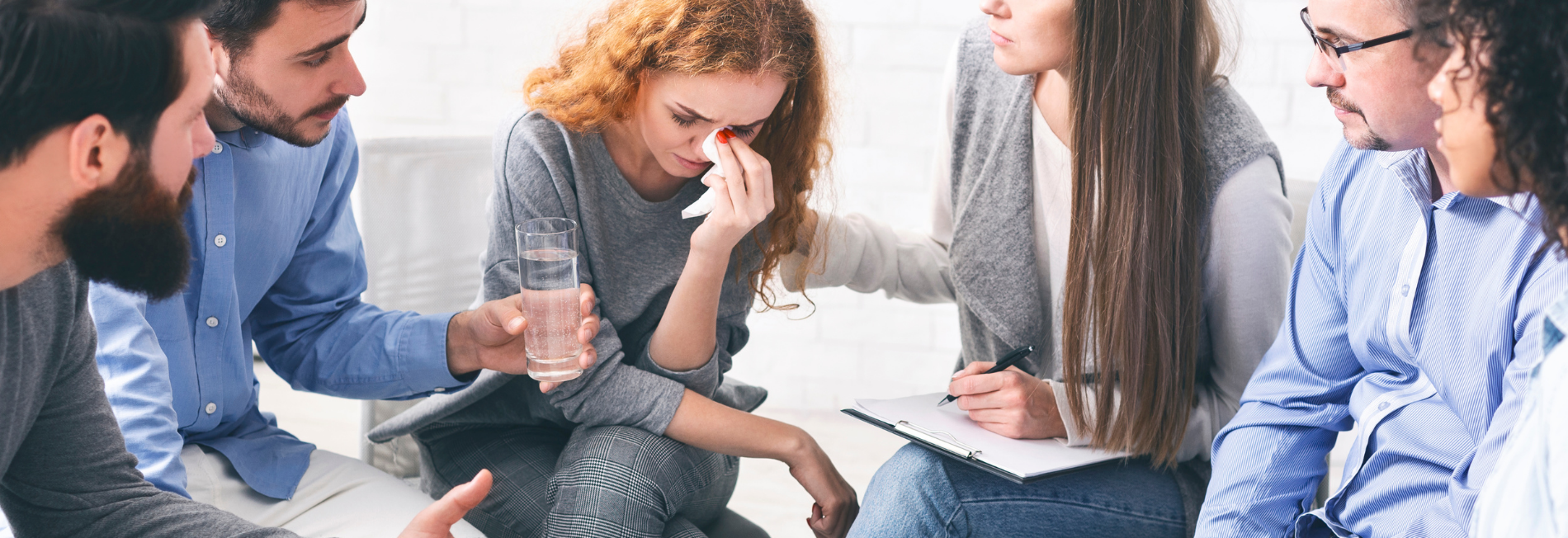 Woman in an substance abuse support group getting emotional in a session. She is comforted by the individuals around her.