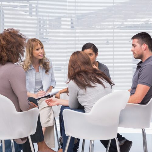 individuals sitting in chairs in a group therapy session